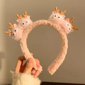 Close-up of a pink plush cartoon headband with cute antler characters.