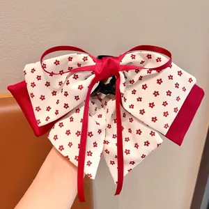 Détail d'une pince à cheveux double épaisseur avec motif floral rouge et nœud ruban