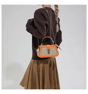Modella con borsa box in paglia intrecciata con finiture arancioni e manico