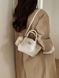 Minimalistische weiße Eimertasche aus Leder mit Silberschloss und Plüschtieranhänger