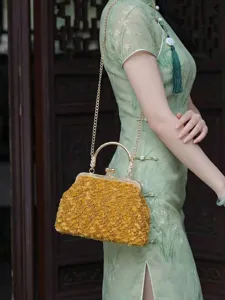 Gros plan d'un sac à main en peluche jaune avec fermoir à baiser doré et bandoulière.