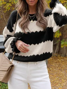 Detailed shot of a stylish black and white colorblock knit sweater paired with white jeans.