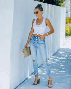 Detailed shot of women's high-waisted multi-button ripped skinny jeans in light blue wash.