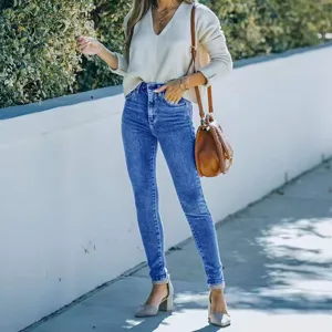 Detailed view of women's stretch skinny jeans styled with a chic casual sweater outdoors.
