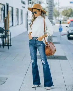 Outdoor street style detail shot showing classic blue washed ripped flare jeans for women.