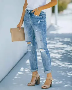 Vue détaillée d'un jean bleu pour femme style destroy avec déchirures et revers aux jambes.