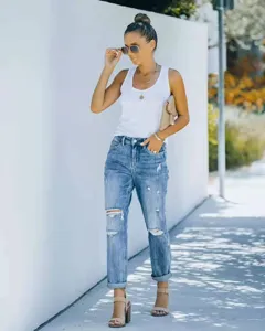 Gros plan détaillé de jolis jeans bleus tendance déchirés aux genoux et à bas retroussés.