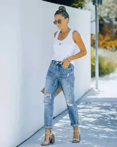 Vue de détail mode en extérieur de jean bleu usé pour femme avec bas de pantalon retourné.