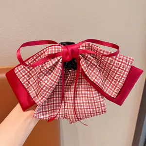 Gros plan d'une pince à cheveux crabe avec nœud à carreaux rouges