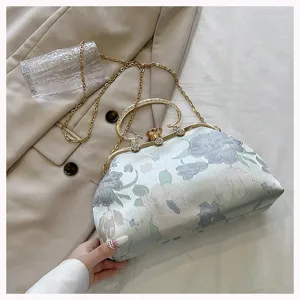 Detailed view of the floral jacquard fabric and metallic gold kiss lock on the shell clutch.