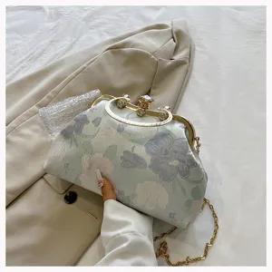 Elegant light blue floral jacquard shell bag with gold clasp and chain strap detail.