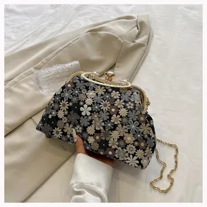 Close-up of vintage jacquard floral shell bag with gold clasp and chain strap.