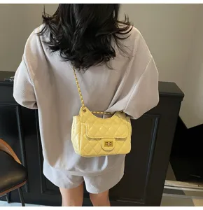 Close-up detail of the yellow quilted shoulder bag featuring gold chain strap and lock