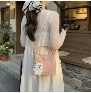 Sac seau rose à texture litchi avec breloque chien blanc en extérieur