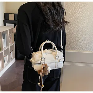 Chic minimalist white bowling pillow bag styled as a crossbody in a lifestyle setting