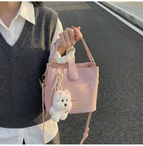 Sac seau rose texture litchi avec charmant porte-clés chiot en peluche blanc.
