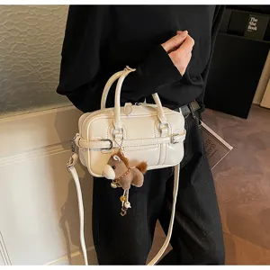 Close-up of a minimalist white patent leather bowling pillow bag with horse charm