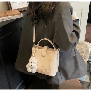 Vue détaillée d'un sac seau beige grainé avec un porte-clés chien blanc pelucheux