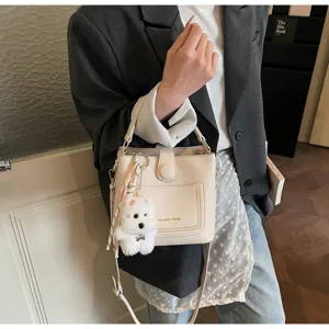 Vue détaillée d'un sac seau crème texturé avec une jolie peluche de chien en pendentif