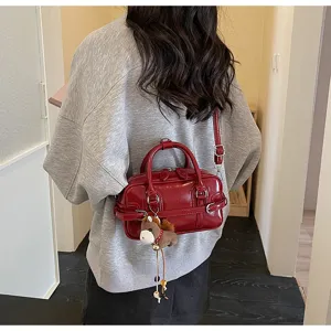 Back view of a stylish red glossy bowling pillow bag worn with a grey sweatshirt.