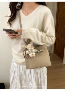 Minimalistische Eimertasche mit Lychee-Struktur, Schloss und Bärenanhänger am Model