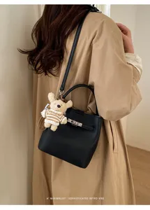 Elegante schwarze Beuteltasche mit Lychee-Muster und Schloss, am Modell gezeigt