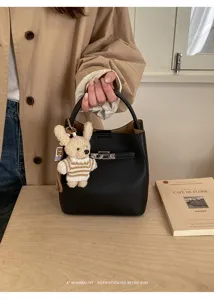 Schwarze Beuteltasche aus genarbtem Leder mit Bärenanhänger und Schloss in Retro-Optik.