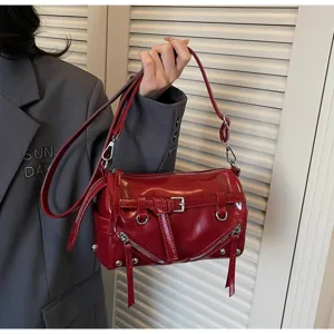 Glossy red vintage pillow bag with belt buckle details held by a model for size reference