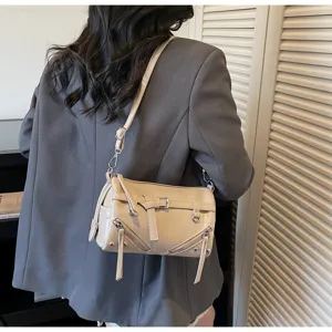 Close-up of the beige shoulder bag showing detailed metal zippers and long leather tassels