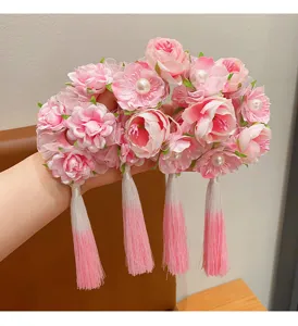 Close-up of pink silk flowers and gradient tassels on an ancient style hair accessory
