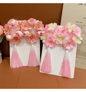 Close-up of children's floral hair rings with pink gradient tassels and silk flowers