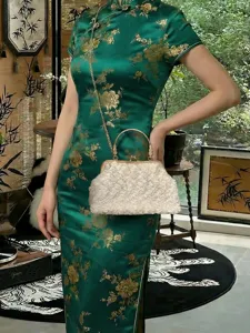 Sac à main en fourrure blanche avec fermoir doré et chaîne porté sur une robe qipao.