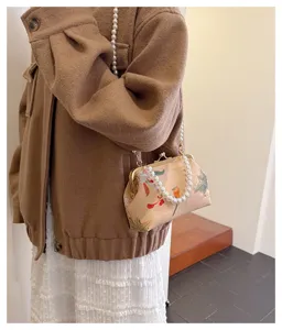 Detailansicht einer Vintage-Stofftasche mit Stickerei und elegantem Perlengriff