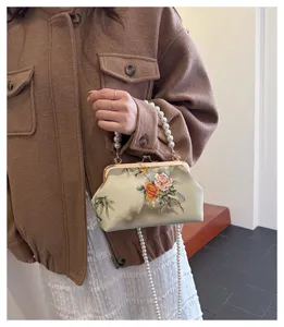Detailansicht einer eleganten bestickten Clip-Tasche mit Perlengriff und langer Perlenkette