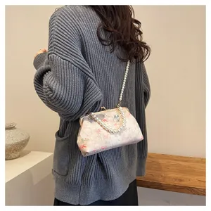 Detail der mit Schmetterlingen bestickten Clip-Tasche mit eleganten Perlenriemen.