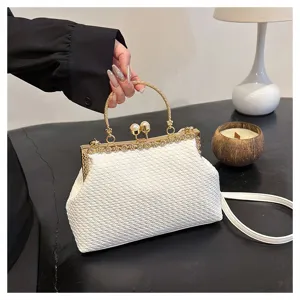 Close-up of white woven texture evening bag with pearl kiss lock and gold handle