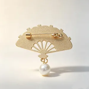 Close-up showing back detail of gold fan brooch with pin mechanism and pearl pendant