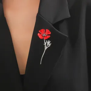 Detailaufnahme einer roten Mohnblumen-Brosche an einem schwarzen Blazer-Revers