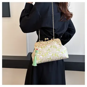 Close-up of elegant floral embroidered handbag with tassel detail and gold chain strap