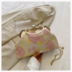 Close-up of elegant floral jacquard shell bag with vintage metal clasp and chain