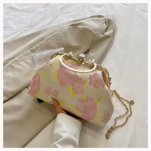 Detail view of floral jacquard clutch bag with gold-tone hardware and chain strap