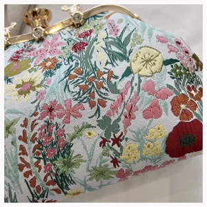 Close-up of floral tapestry fabric and gold kiss-lock clasp on a shell bag.
