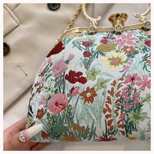 Close-up of elegant floral jacquard shell bag with gold clasp and rhinestone handle.