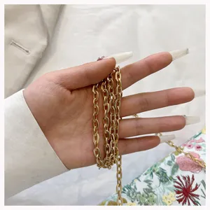 Close-up detail of golden oval link chain strap on floral jacquard fabric crossbody bag