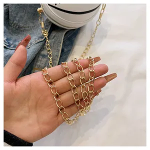 Close-up of golden chain strap on a white basketball-shaped mini crossbody bag