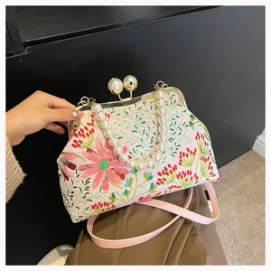 Detailansicht der eleganten Abendtasche mit Blumenstickerei und feinem Perlengriff.
