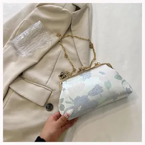 Detailansicht einer eleganten Muscheltasche mit Blumenstickerei und goldener Kette