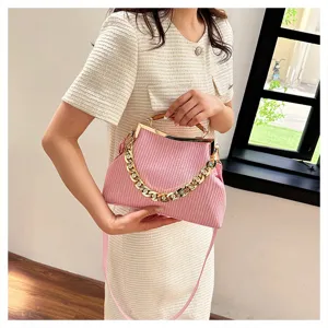 Pink embossed stripe handbag with gold chain held by a woman in a cream dress