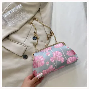 Detailansicht einer eleganten, floral bestickten Muscheltasche mit goldener Kette