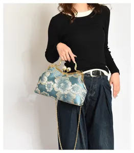 Detalle de un bolso vintage azul verdoso con bordado floral y cierre de perlas para mujer elegante.